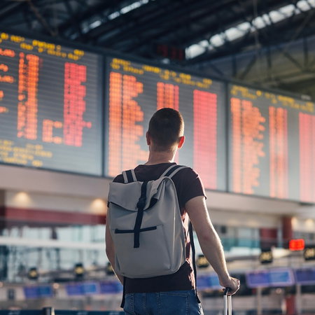 A traveller looks at an airport departures board after flight cancellations, highlighting the importance of knowing your passenger refund rights.