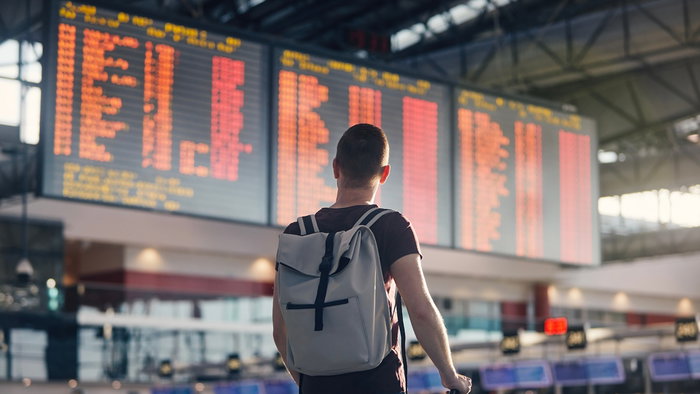 A traveller looks at an airport departures board after flight cancellations, highlighting the importance of knowing your passenger refund rights.