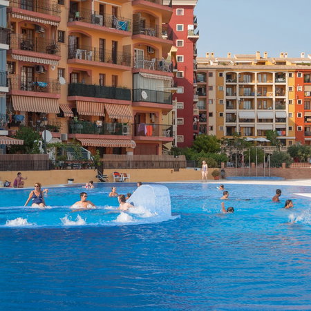 Residents enjoy a communal swimming pool outside an apartment complex in Spain.