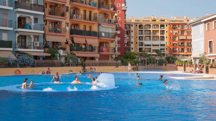 Residents enjoy a communal swimming pool outside an apartment complex in Spain.