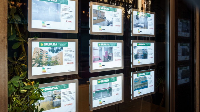 Property listings displayed in the window of a Spanish estate agency, reflecting rising house prices and strong demand across the housing market.