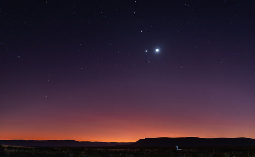 A rare planetary alignment shines above the horizon at dusk, with several bright planets visible in the night sky.