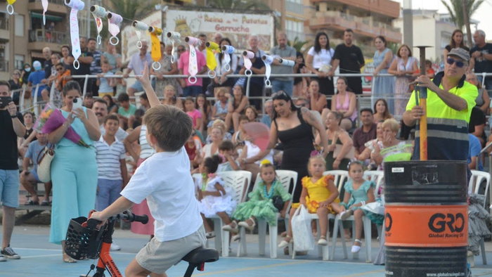 Young boy ride a bike, trying to reach for a decorated ribbon at Garrucha's traditional ribbon race