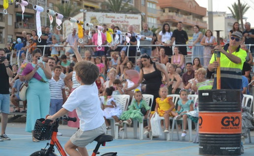 Young boy ride a bike, trying to reach for a decorated ribbon at Garrucha's traditional ribbon race