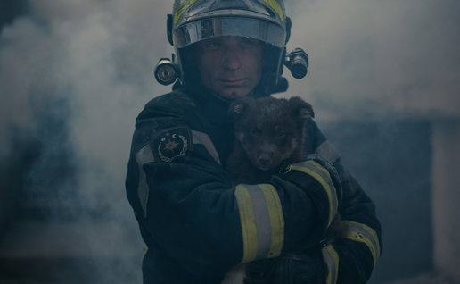 Firefighter coming through smoke carrying a small dog