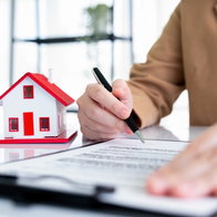 A women is finalising the sale of her house, signing paperwork.