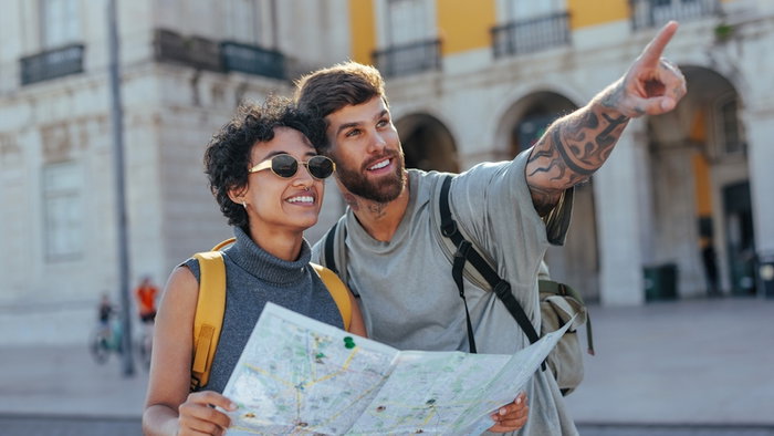 Happy tourists holding a map and pointing excitedly while exploring a European country