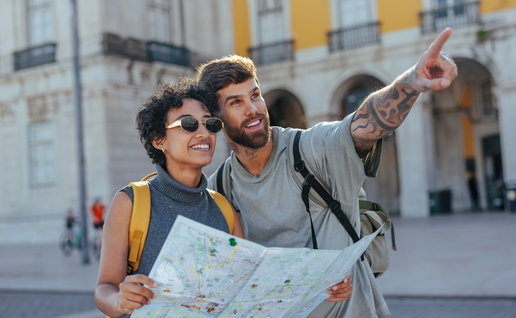 Happy tourists holding a map and pointing excitedly while exploring a European country