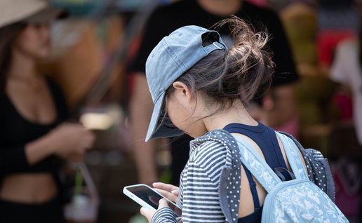 Woman with rucksack on her back with a cap on her head and looking at a mobile phone