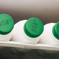 Fresh milk on a refrigerator shelf with expiration dates visible on the lids