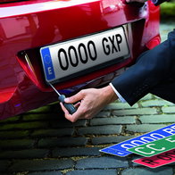 A technician fits a Spanish vehicle registration plate to a newly registered car, reflecting the latest DGT number plate series introduced in July 2026.