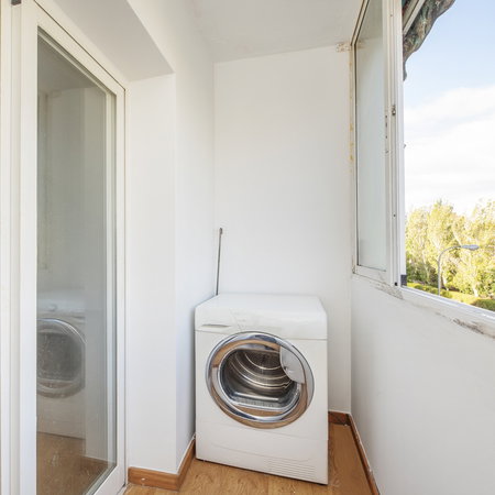 A washing machine installed on a narrow apartment balcony in Spain.
