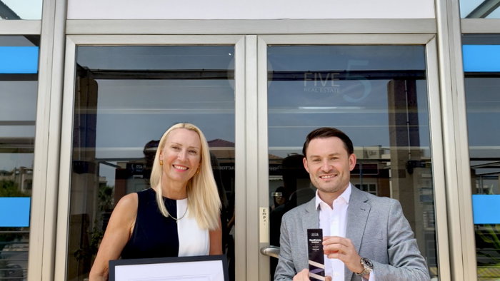 Outside of Five Real Estate offices with staff holding the award