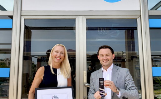 Outside of Five Real Estate offices with staff holding the award