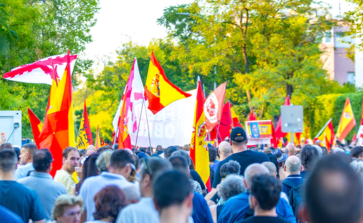 A crowd holding Spanish and regional flags at a street demonstration in Madrid