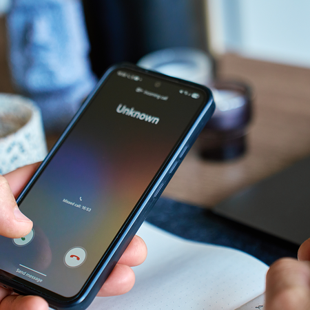 Person holding a phone while an unknown number calls them.