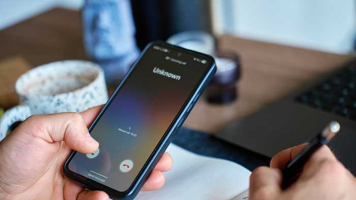 Person holding a phone while an unknown number calls them.
