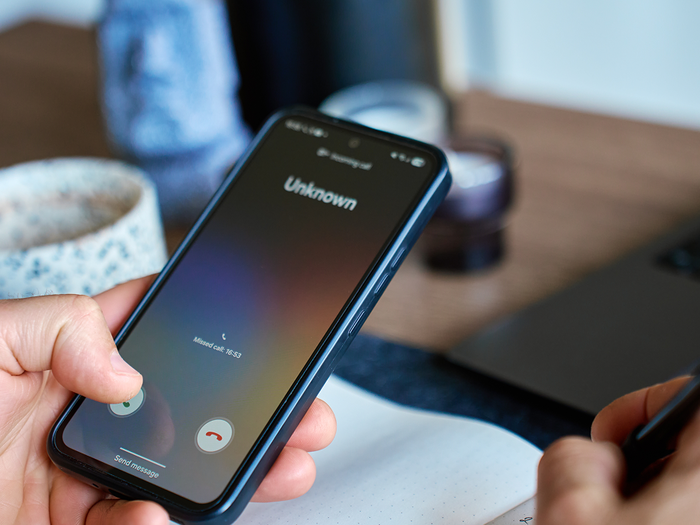 Person holding a phone while an unknown number calls them.