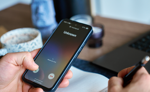 Person holding a phone while an unknown number calls them.
