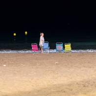 Beachgoer setting out deckchairs on Benidorm beach at night