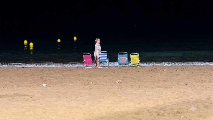 Beachgoer setting out deckchairs on Benidorm beach at night