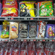 A hospital vending machine stocked with crisps, chocolate bars and biscuits on the top two rows and bottled water on the bottom row.