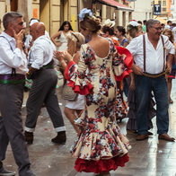 Revellers in flamenco dresses dancing on a crowded street during Málaga's Feria.