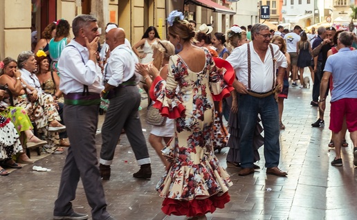 Revellers in flamenco dresses dancing on a crowded street during Málaga's Feria.