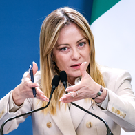Italian Prime Minister Giorgia Meloni speaking into a microphone at a podium.