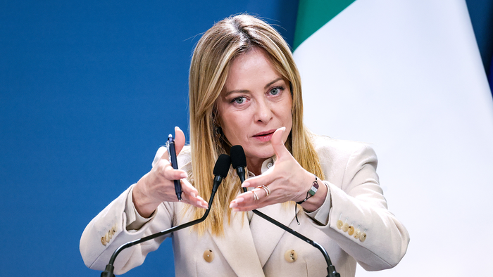Italian Prime Minister Giorgia Meloni speaking into a microphone at a podium.