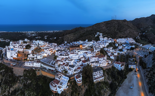 Aerial night view of Mojácar's hillside town lit up above the Almería coastline