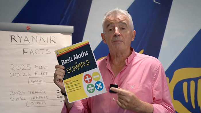 Michael O'Leary holding a book called "Math for Dummies" in front of a Ryanair branded wall during his speech in a recent YouTube video.