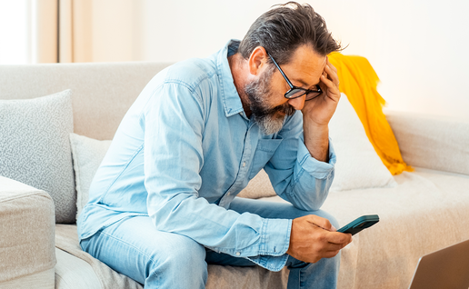 Person holding their head in their hand as they look worried at their phone.