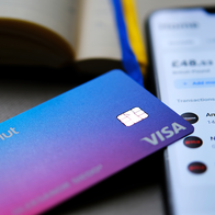 A revolut debit card resting on a phone with the Revolut app open.