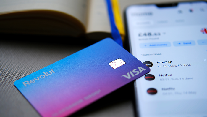 A revolut debit card resting on a phone with the Revolut app open.