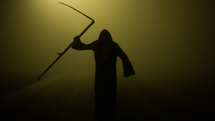 A dark figure dressed as the grim reaper coming out from the fog