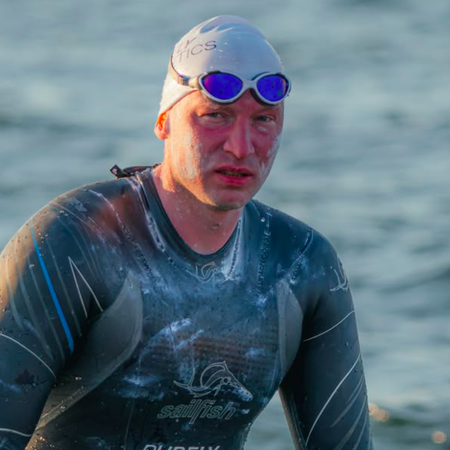 A man emerging from the ocean in a wetsuit