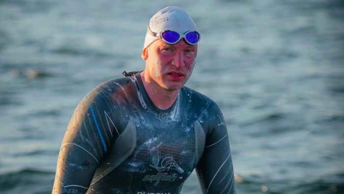 A man emerging from the ocean in a wetsuit