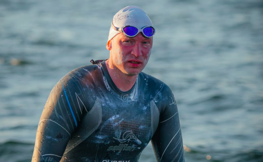 A man emerging from the ocean in a wetsuit