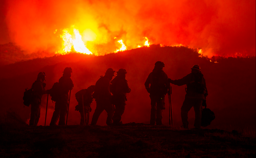 The silhouette of firefighters with the flames of a wildfire behind them