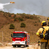 Firefighters in Spain fighting a forest fire with a fire truck in the background