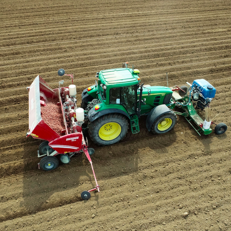 A farmer cultivating potatoes from his John Deere tractor in France