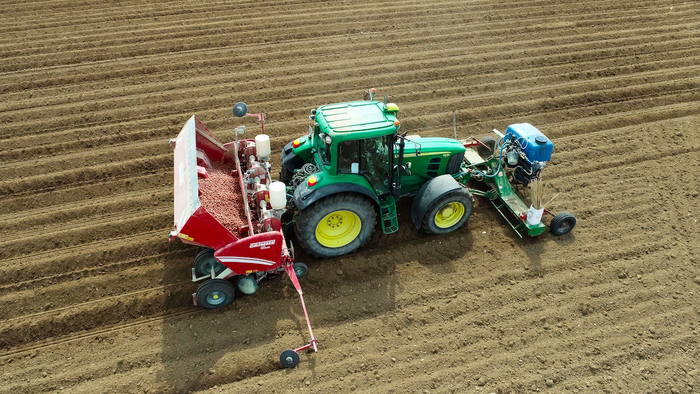 A farmer cultivating potatoes from his John Deere tractor in France