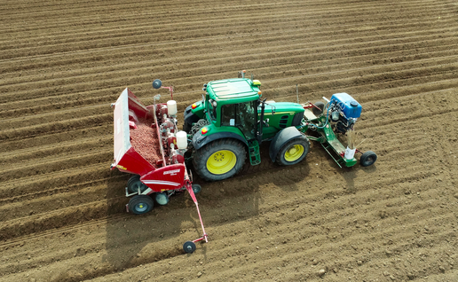 A farmer cultivating potatoes from his John Deere tractor in France