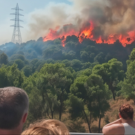 onlookers watching as flames from wildfire tear through scrubland in Barcelona