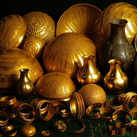 Collection of ancient gold bowls, vases, bracelets, and ornaments arranged on a dark green surface.