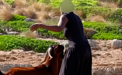 Woman in dark dress with face censored, standing beside a brown goat on rocky terrain.