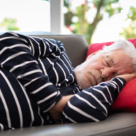 Elderly man sleeping on a sofa.