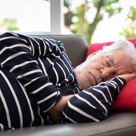 Elderly man sleeping on a sofa.
