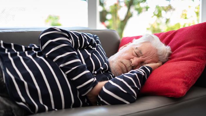 Elderly man sleeping on a sofa.